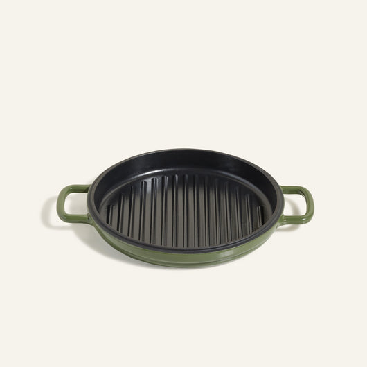 The Cast Iron Hot Grill is a round, green enameled cast iron grill pan with two handles and a ridged black surface—ideal for indoor grilling, shown against a plain light background.