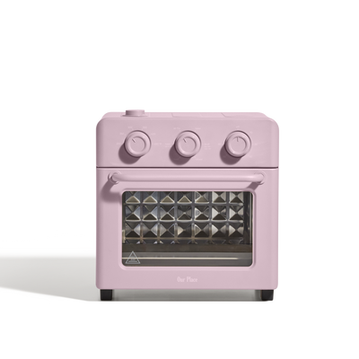 The AU - Wonder Oven is a compact pink toaster oven with three control knobs, a glass door, and air fryer functionality, shown against a plain white background for a stylish and healthy cooking solution.