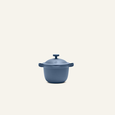 The Petite Perfect Pot, a small blue cast iron pot with a matching lid and side handles, is centered on a plain light background.