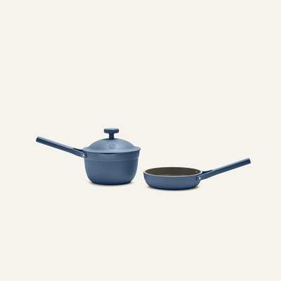 The Tiny Cookware Duo, featuring a blue saucepan with lid and a matching blue frying pan, is displayed side by side against a simple light background.