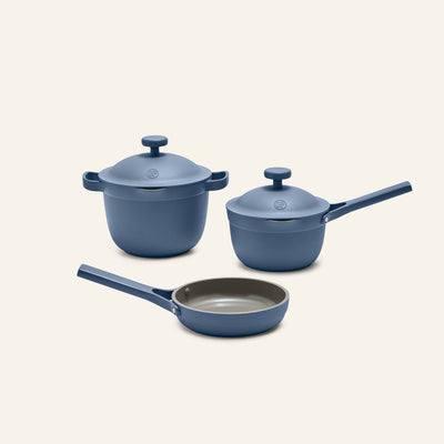 The Tiny Cookware Duo + Petite Perfect Pot in blue, each with lids and handles, are displayed on a plain light background.