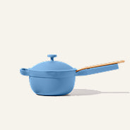 A light blue ceramic saucepan with a lid and a light wood handle, shown on a solid off-white background.