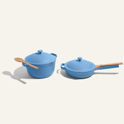 Blue non toxic cookware set - pots and pans set with wooden handles on a light gray background