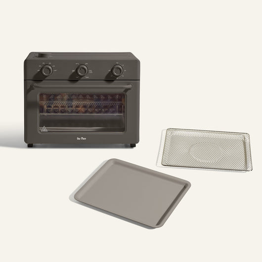 The Large Wonder Oven + Large Wonder Oven Essentials Kit is displayed in black, with a wire rack and baking tray placed in front of it against a simple background.