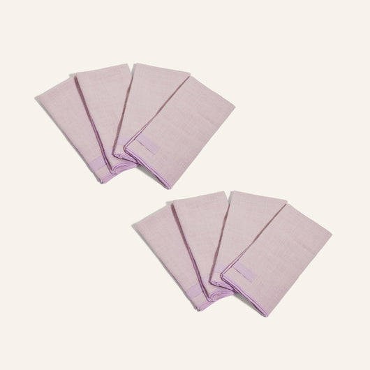 Two sets of four folded light purple Loop Napkins are arranged on a plain light background.