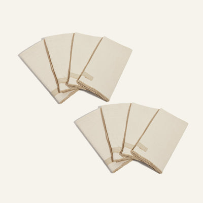 Two sets of Loop Napkins in beige, each with a built-in loop ring, are folded neatly and arranged on a light background.