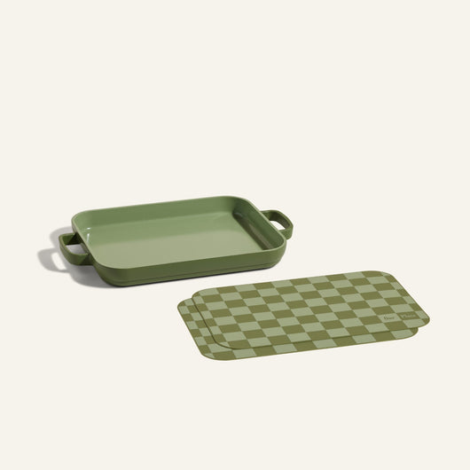 Mini Griddle Pan with handles displayed beside matching Mini Oven Mats in green checker pattern, shown on a light background.