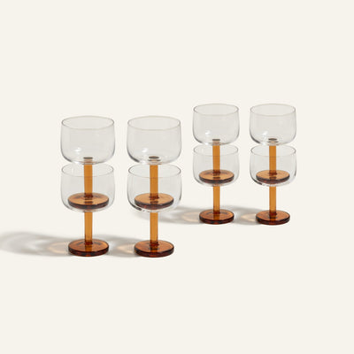 Six Party Coupes with clear bowls and amber-colored stems are arranged in two rows on a neutral background, making a stylish set of glassware perfect for parties.