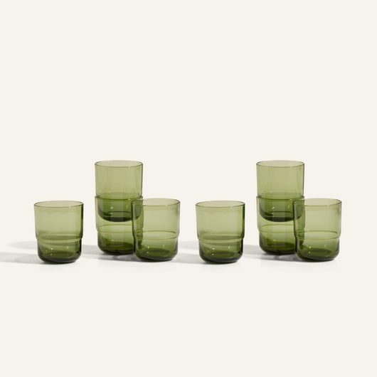 Six Short Night + Day Glasses in green recycled glass are arranged in two stacks of two and two singles, all set on a plain off-white background.
