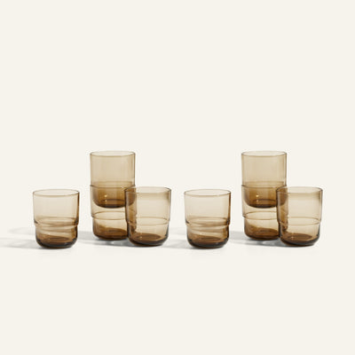 Six amber-colored Short Night + Day Glasses, made from recycled glass and arranged in two rows, with three taller than the others—versatile drinkware ideal for any occasion.