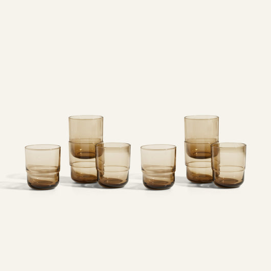 Six amber-colored Short Night + Day Glasses, made from recycled glass and arranged in two rows, with three taller than the others—versatile drinkware ideal for any occasion.