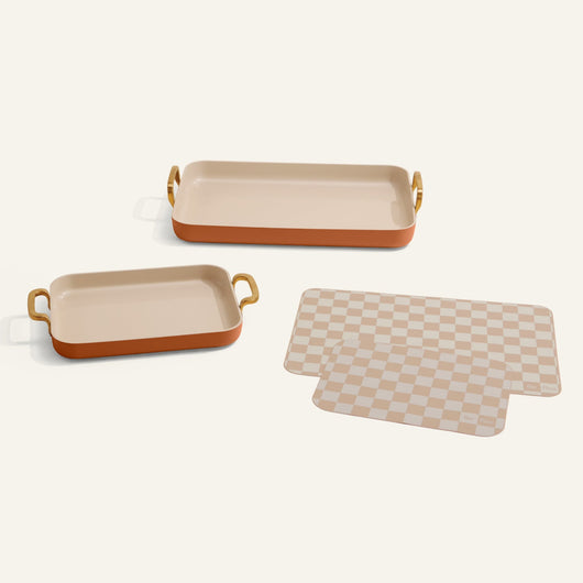 Two rectangular trays with handles and a checkered mat on a white background