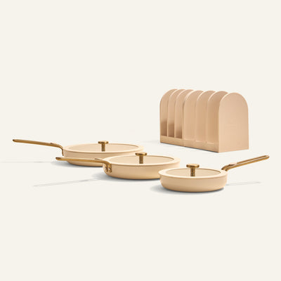 Set of three beige frying pans with gold handles on a white background