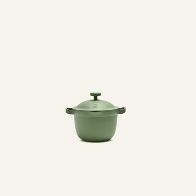 The Petite Perfect Pot, a small matte green pot with two side handles and a lid, is centered on a plain light background.