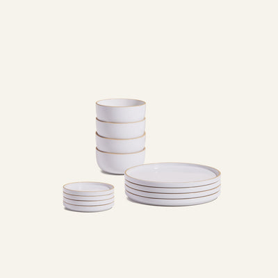 The Plates & Bowls Set features white ceramic dishes with gold rims, including four bowls, four plates, and four small dishes stacked neatly against a plain background.