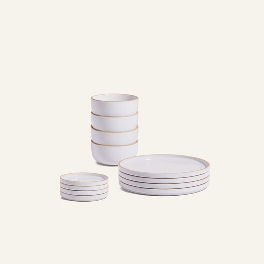 The Plates & Bowls Set features white ceramic dishes with gold rims, including four bowls, four plates, and four small dishes stacked neatly against a plain background.