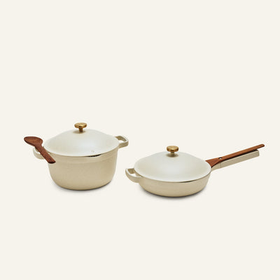 The Cookware Duo features two cream-colored pots with lids—a round Dutch oven with a wooden spoon and a skillet with chopsticks—perfect as a compact alternative to an 18-piece set and ideal for any kitchen.
